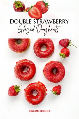 White background with bright red strawberry glazed doughnuts and fresh strawberries